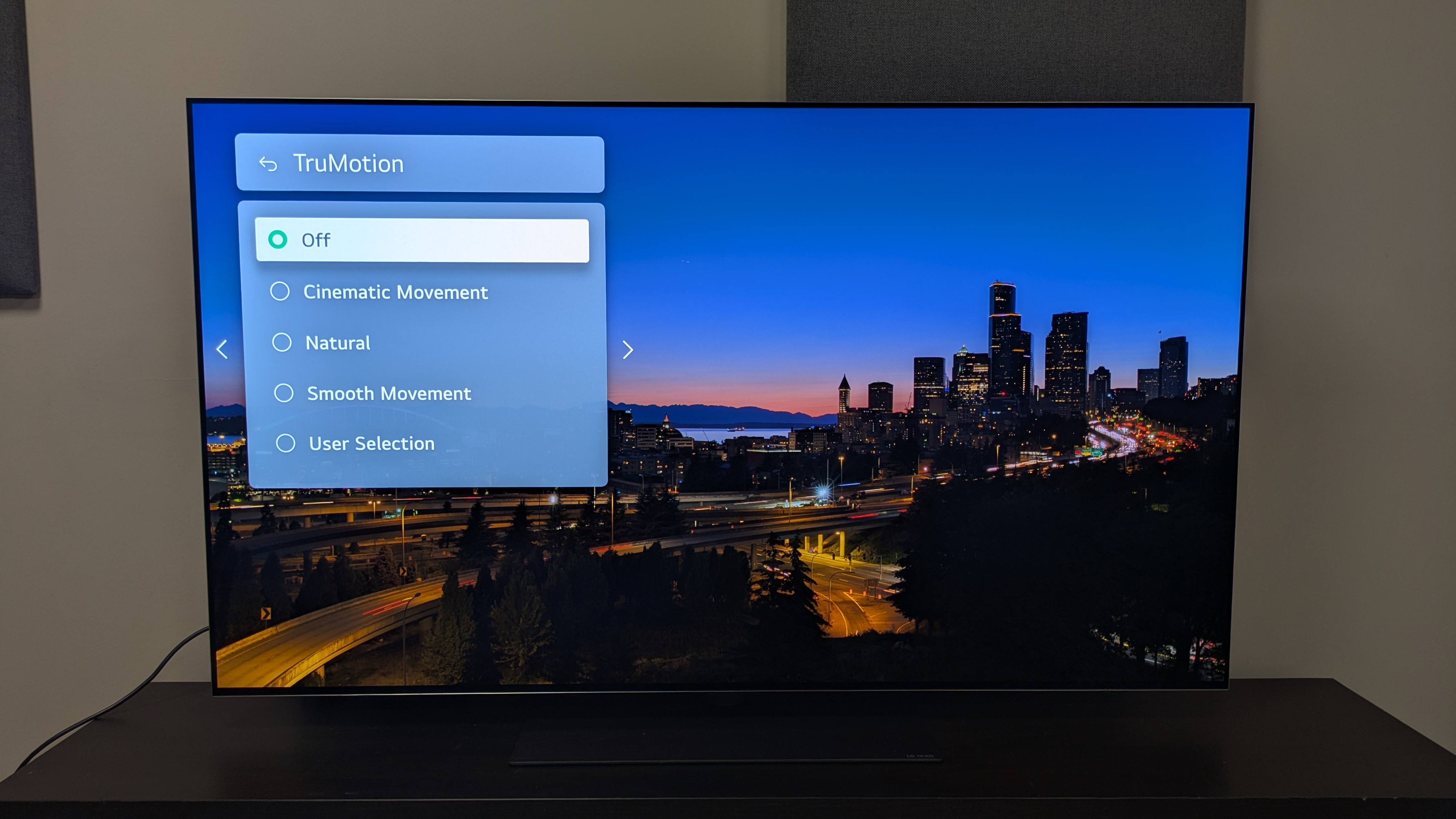 LG G5 OLED TV with motion settings menu on screen over picture of city landscape at night
