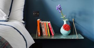 Blue bedroom with floating shelf nightstand to highlight decluttering as a key spring cleaning tip for apartments and small spaces