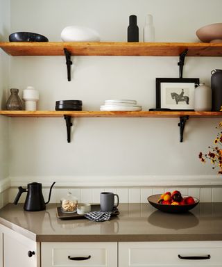 A kitchen with gray walls and open wooden shelving