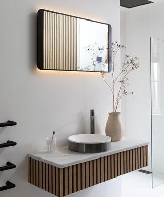 black bathroom mirror with backlight on wall above wooden and marble wall mounted vanity unit