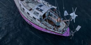 Jessica Watson standing on a boat with her arms in the air as it rains