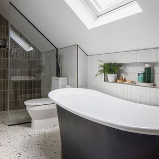 Loft bathroom with blue freestanding bath and shower cubicle with sloped shower screen