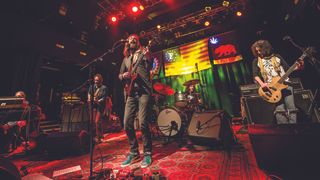 Chris Robinson Brotherhood playing a song on stage, standing on a red patterned rug.