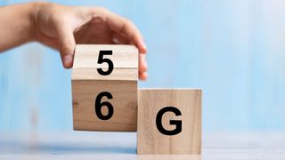 A hand changing a wooden block from 5G to 6G 