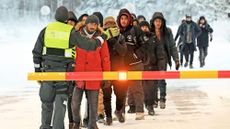 A line of migrants waits to speak with a guard at a border crossing in Finland