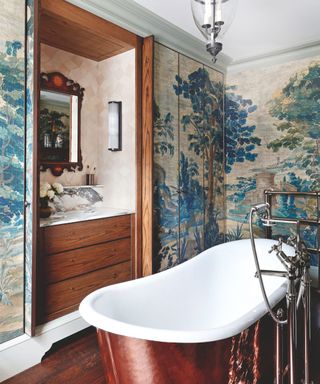 bathroom with blue nature patterned wallpaper and copper bath