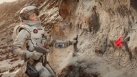 a woman in a spacesuit doing geological tests