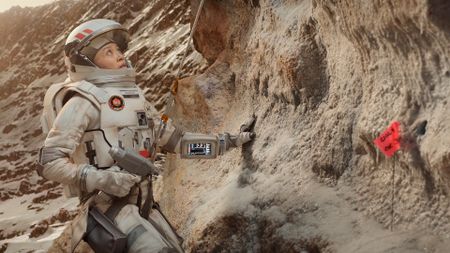 a woman in a spacesuit doing geological tests