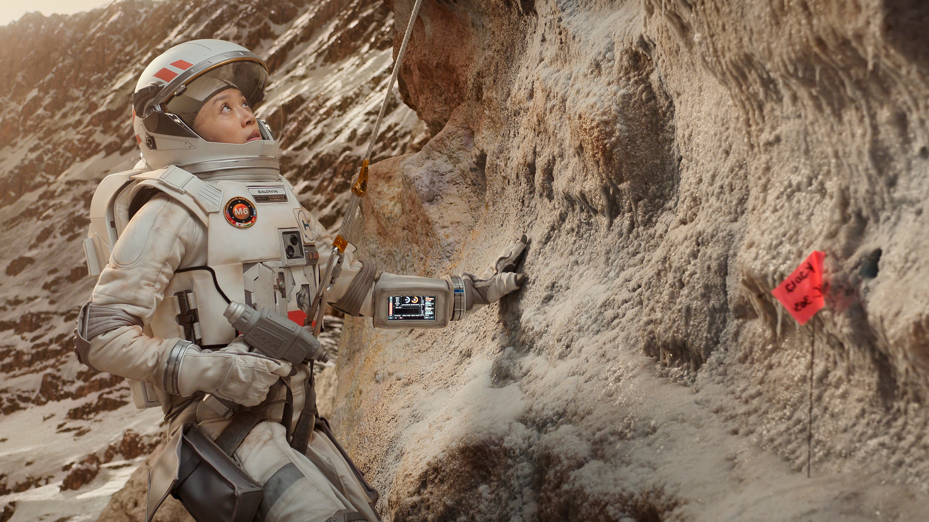 a woman in a spacesuit doing geological tests
