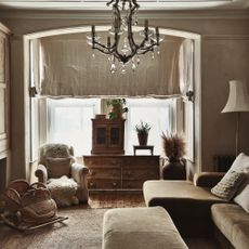 neutral sitting room with linen curtain, raw wood furniture, green velvet corner sofa and rush rug