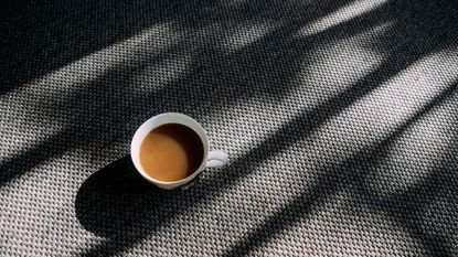 Cup of coffee with milk on grey carpet