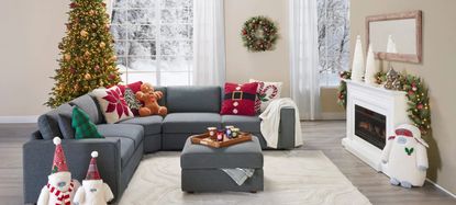 A living room with assorted Christmas decorations in it and a snowy landscape outside of the window.