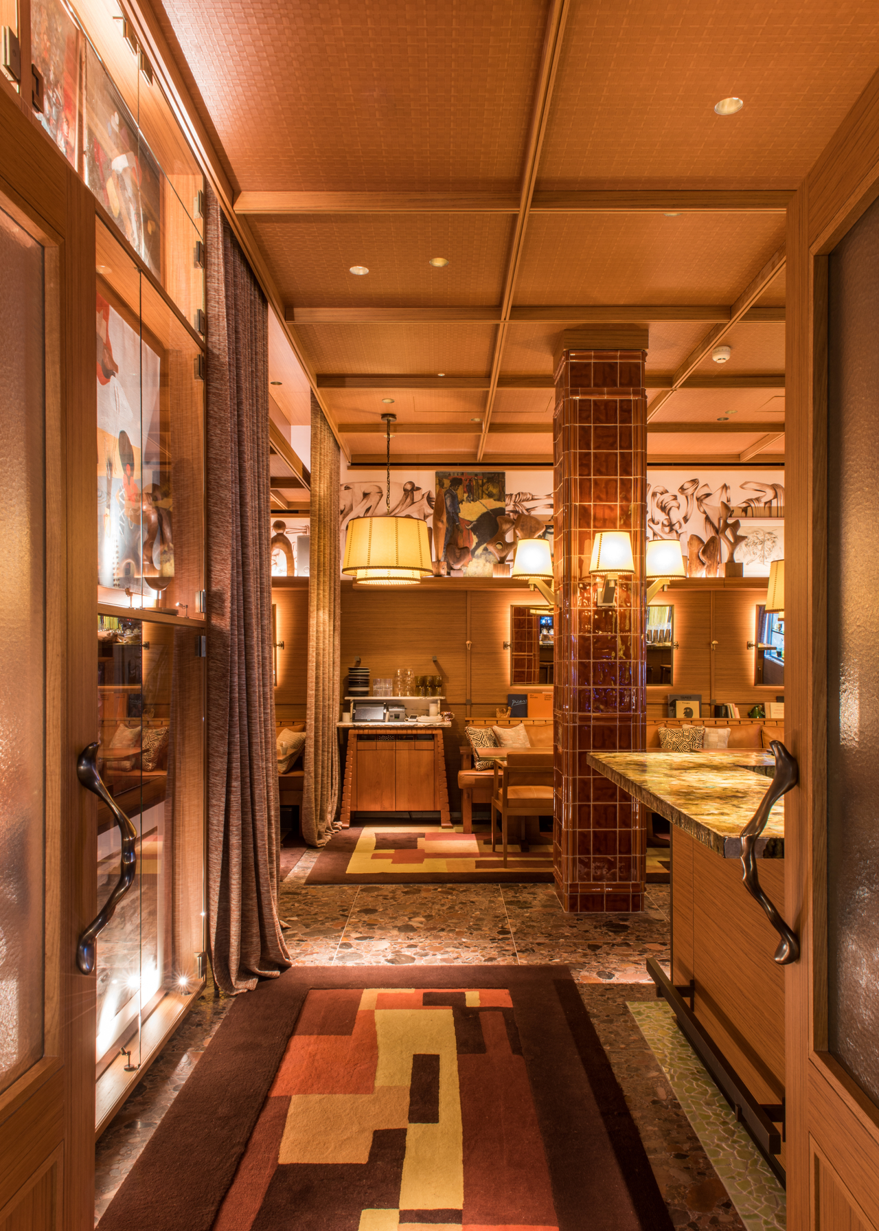 A hotel restaurant with tiled pillars, warm lighting and walls of art