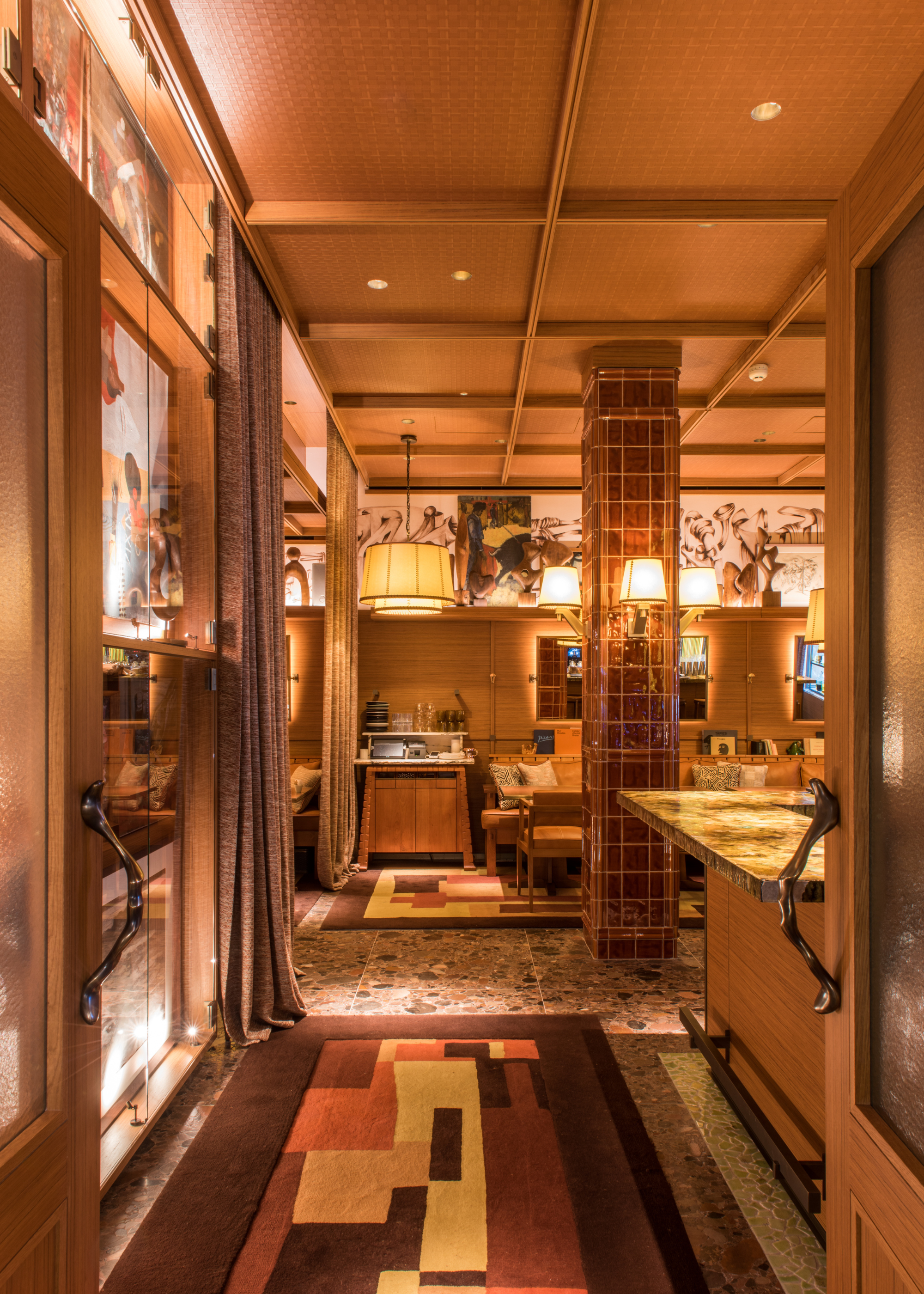 A hotel restaurant with tiled pillars, warm lighting and walls of art