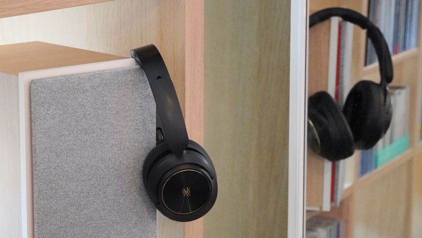 The OneOdio Focus A6 headphones hanging from a light and speaker.
