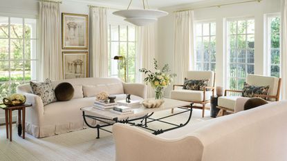 warm minimalist living room with all neutral decor, a wrought iron coffee table, arm chairs with foliage printed cushions and a skirted couch