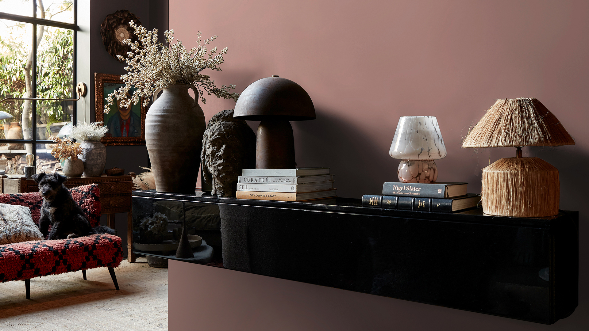 Brown wall with a shelve full of lamps and vase in a living room with crittal-style windows