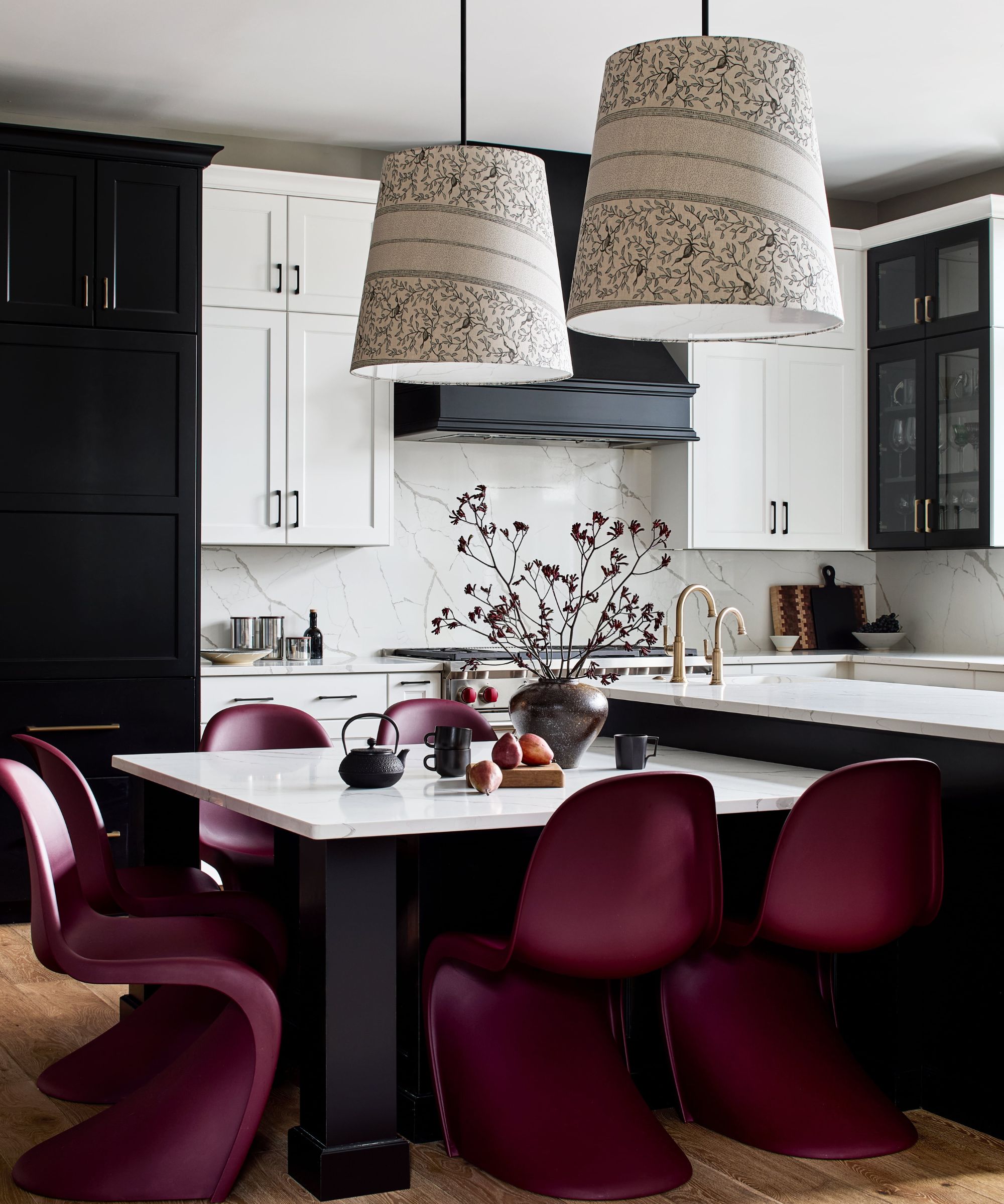 Kitchen with marble backsplash and countertops and black cabinetry with a breakfast table at the centre with purple dining chairs around it