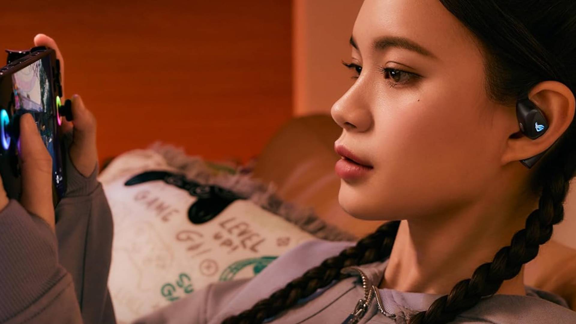 Image of a person playing a handheld while wearing the ROG Cetra open wireless earbuds.