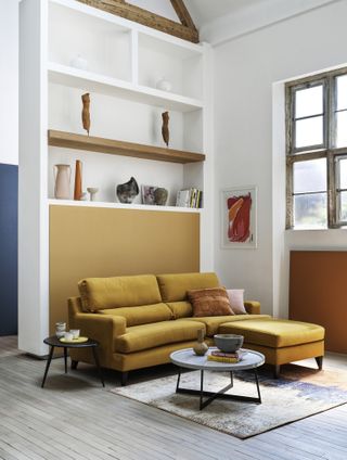 living room with yellow sofa, round side tables, textured rug, shelving, open plan feel