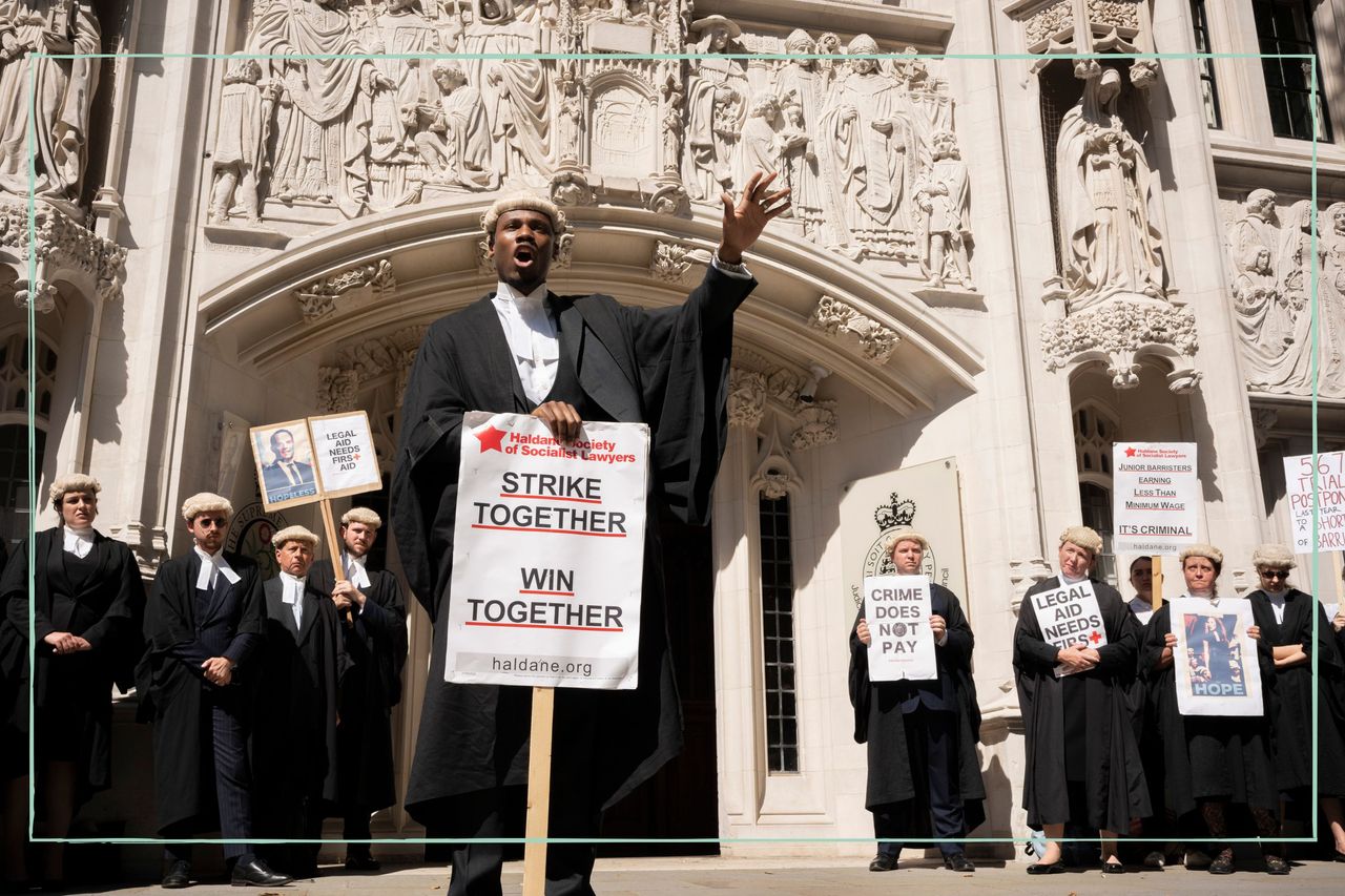 Striking barristers in their wigs and gowns holding placards reading &#039;strike together win together&#039; 