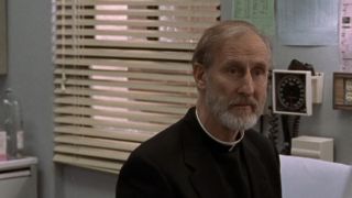 James Cromwell dressed as a priest and looking serious in ER