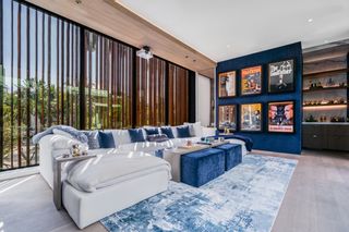 movie room with wooden elements, blue accents, bookshelf, white sectional, blue rug, blue footstools/coffee tables, view to exterior, blinds