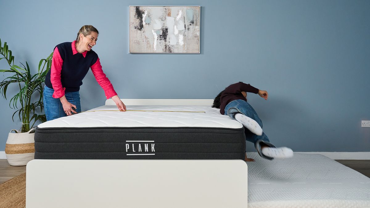 Testing the edge support of the Plank Firm Luxe mattress in our Sleep Lab. On the left, Nicola Appleton uses a tape measure to see how close Becky George is to the edge of the bed. On the right, Becky George is falling off the mattress on to a waiting crash pad