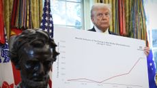 President Donald Trump holds up economic data charts