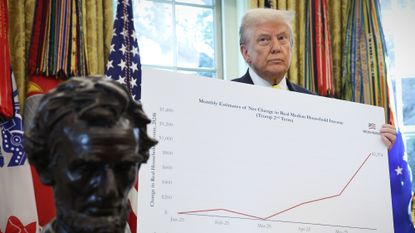 President Donald Trump holds up economic data charts