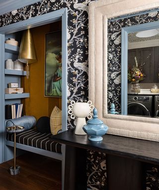 An entryway with a seating nook and bookshelves, a console table and a large white mirror