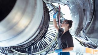 A female mechanic works on an airplane engine