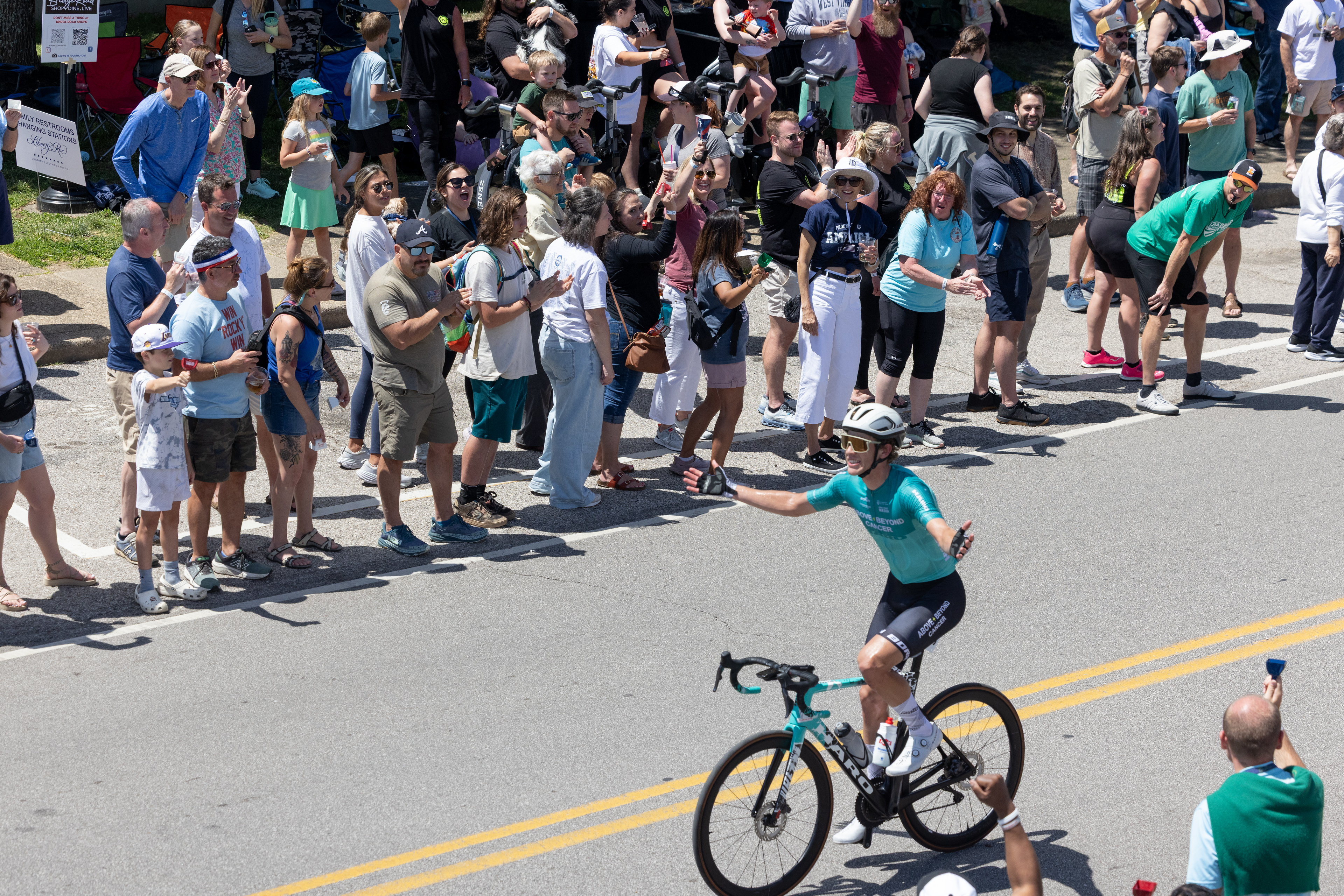 Luke Arens (Above + Beyond Cancer Cycling Team) tries to pump up the crowd as he makes his way up the Bridge Street climb.