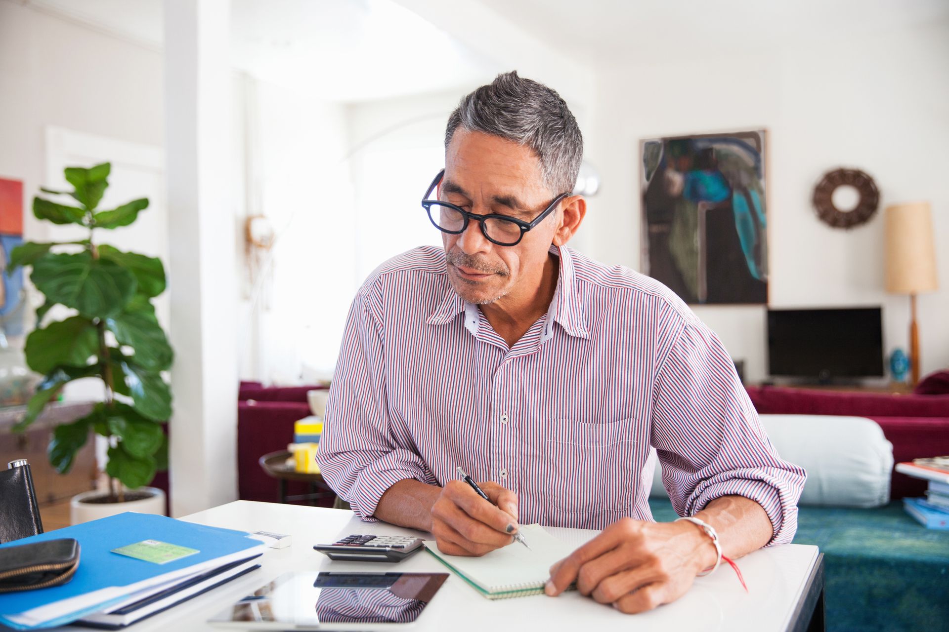 Mature man wearing eyeglasses working on personal finances at home