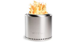 Stainless steel solo stove shown on a white background with fire coming out the top.