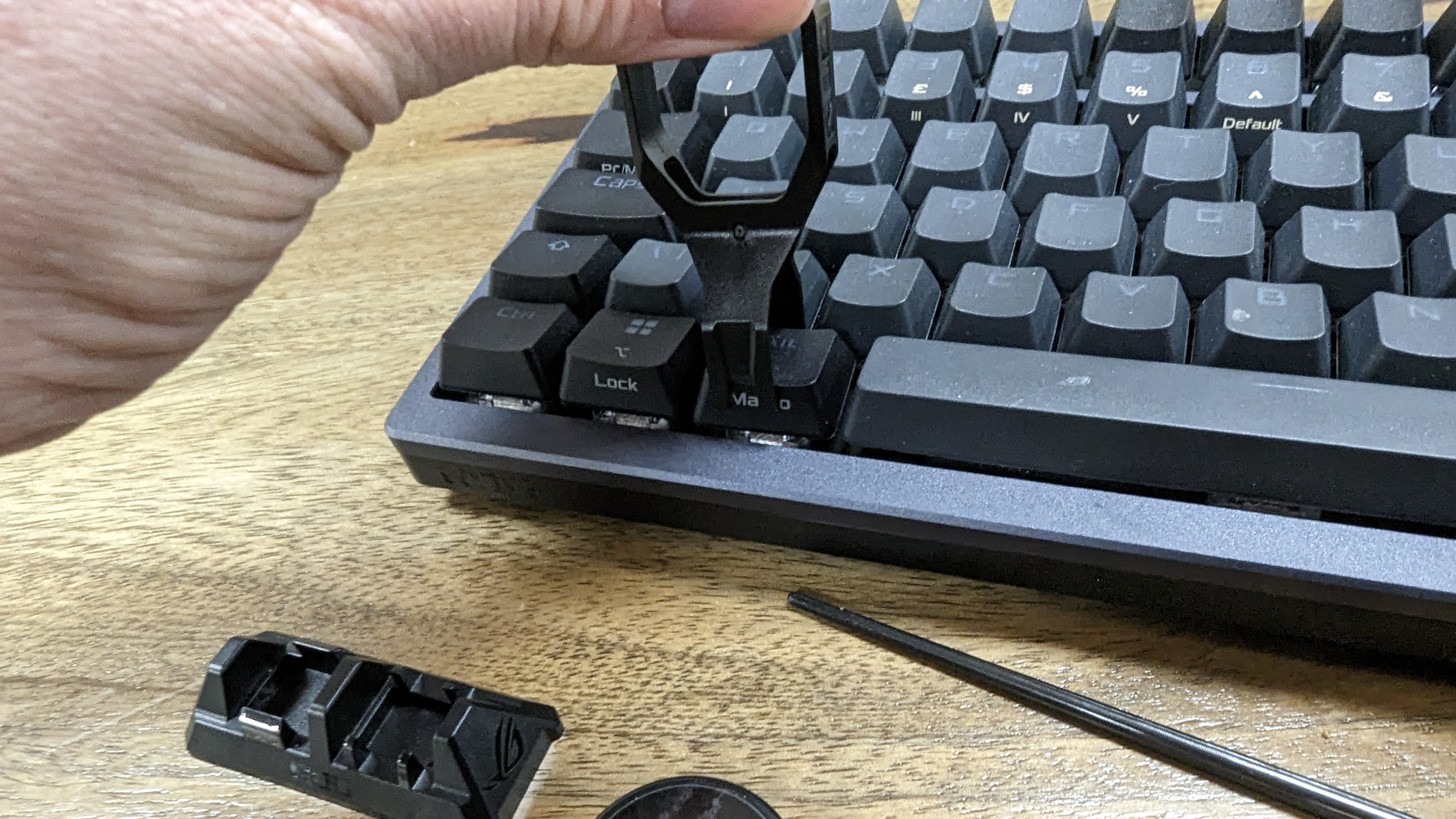 Asus ROG Azoth wireless gaming keyboard with RGB lighting on a wooden desk