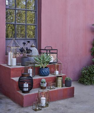 pink steps leading up to a door with candles and plants on them