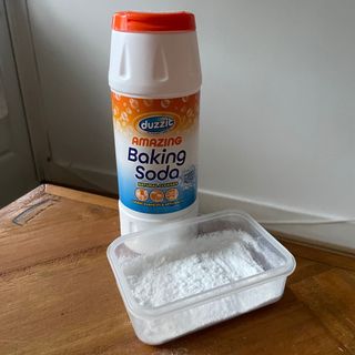 Bottle of baking soda next to a plastic pot full of baking soda