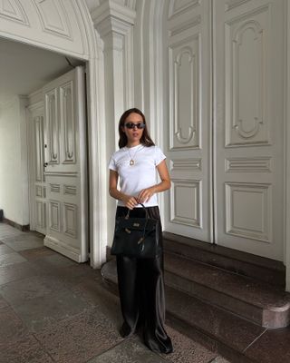 Influencer wears black satin trousers.