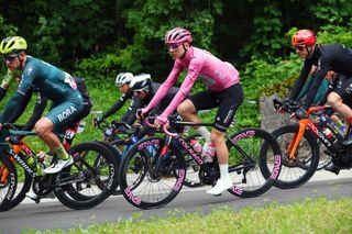 Team UAE's Slovenian rider and overall leader's pink jersey Tadej Pogacar (C) and Team Bora's German rider Jonas Koch (L) ride in the pack during the 18th stage of the 107th Giro d'Italia cycling race, 206km between Fiera di Primiero and Padua on May 23, 2024. (Photo by Luca Bettini / AFP)