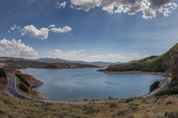 The peloton gets strung out as they pass a lake along the route.