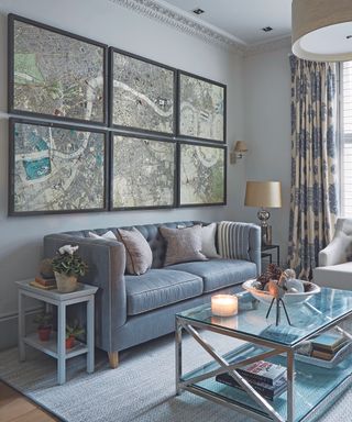 A grey living room with framed map prints and glass coffee table.