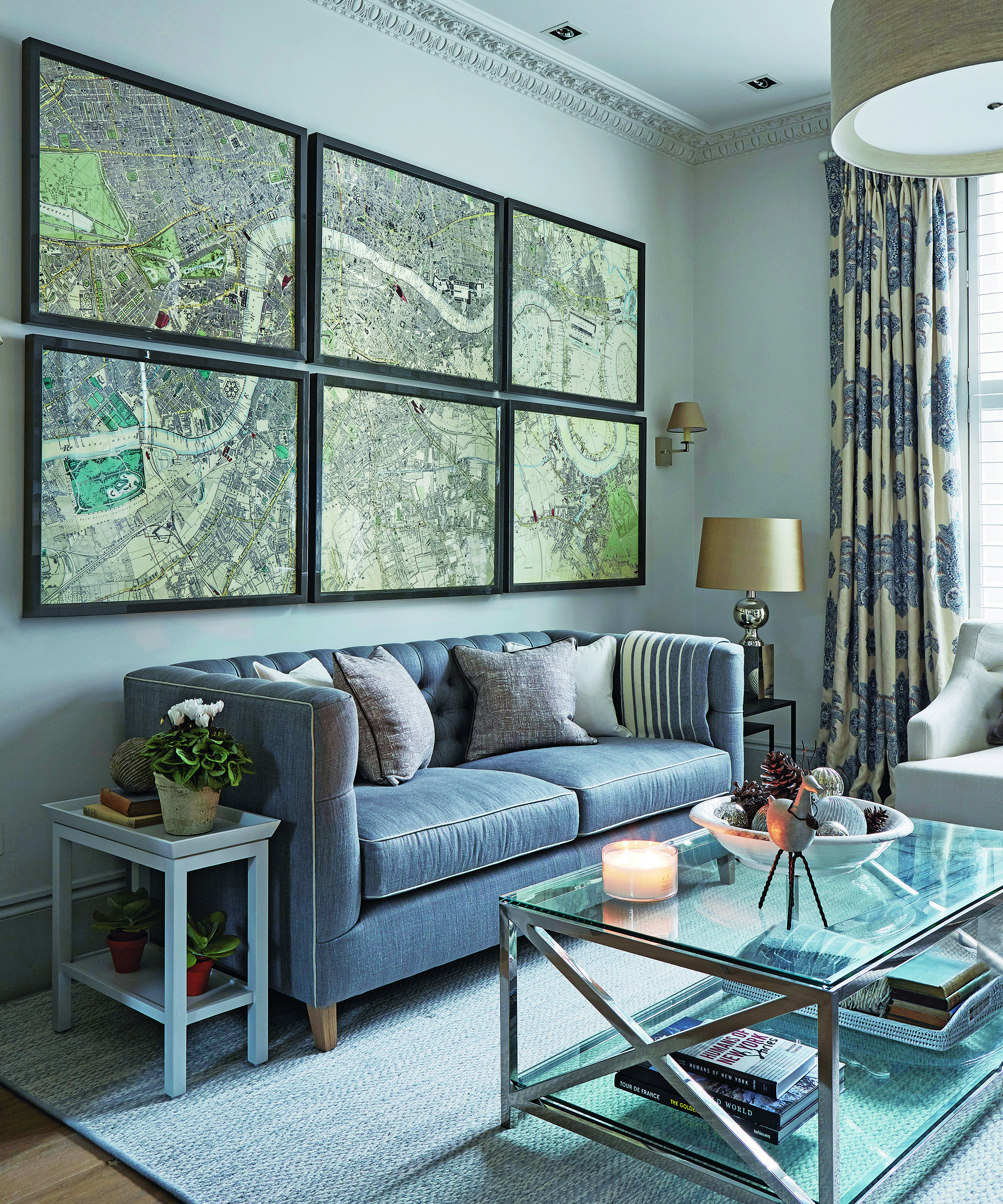 A grey living room with framed map prints and glass coffee table.