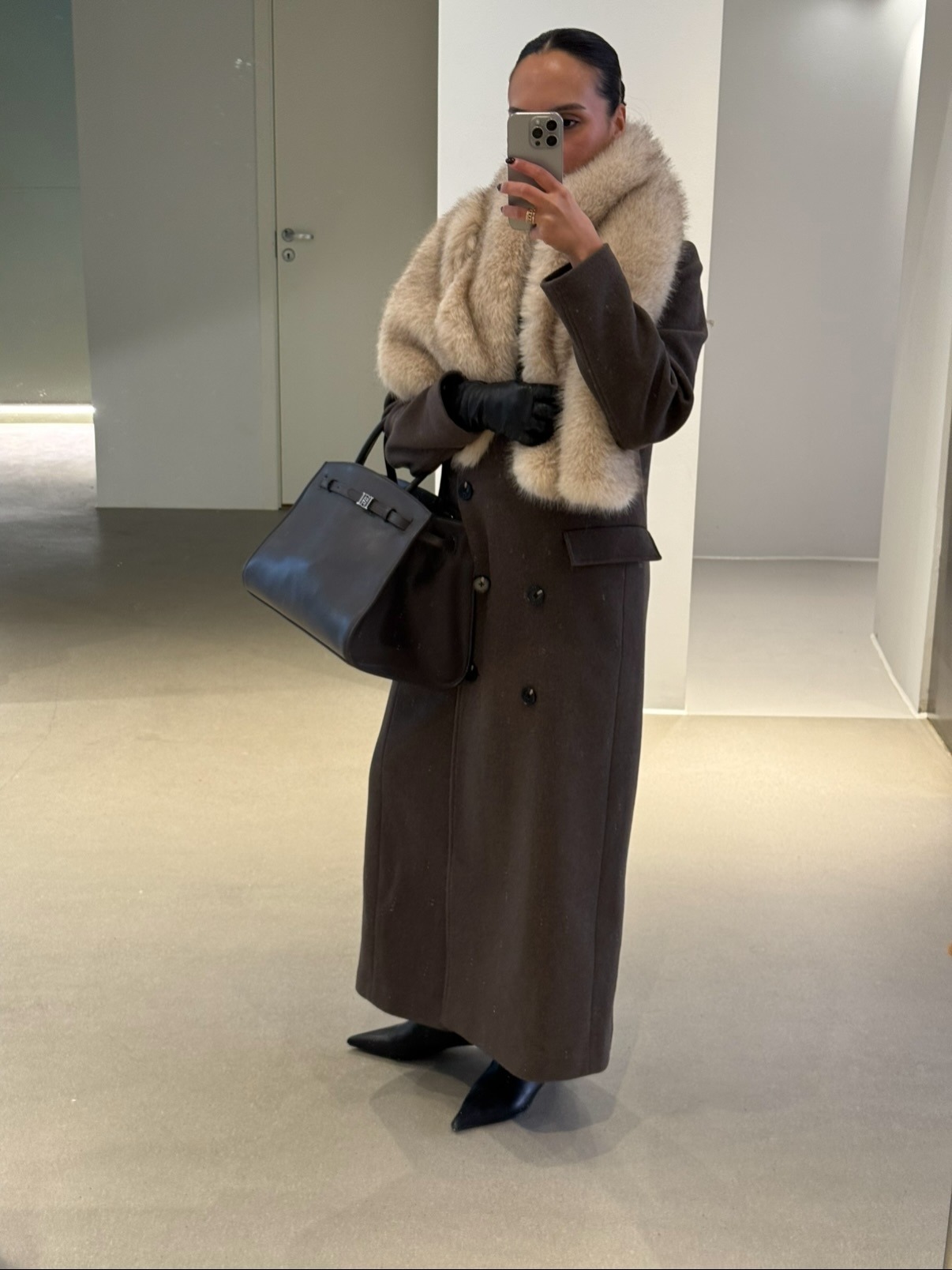 @ingridedvinsen wears a double-breasted brown coat with a black leather bag, pointed-toe boots and a fur scarf.
