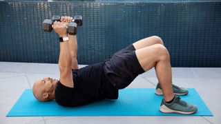 Man lifting weights while wearing Fitbit Versa 2