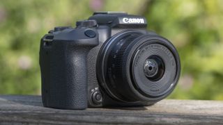 The Canon EOS R10 camers sitting on a wooden bannister