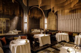 A plush restaurant features Renaissance-inspired walls mixed with mid-century modern luxury furniture.