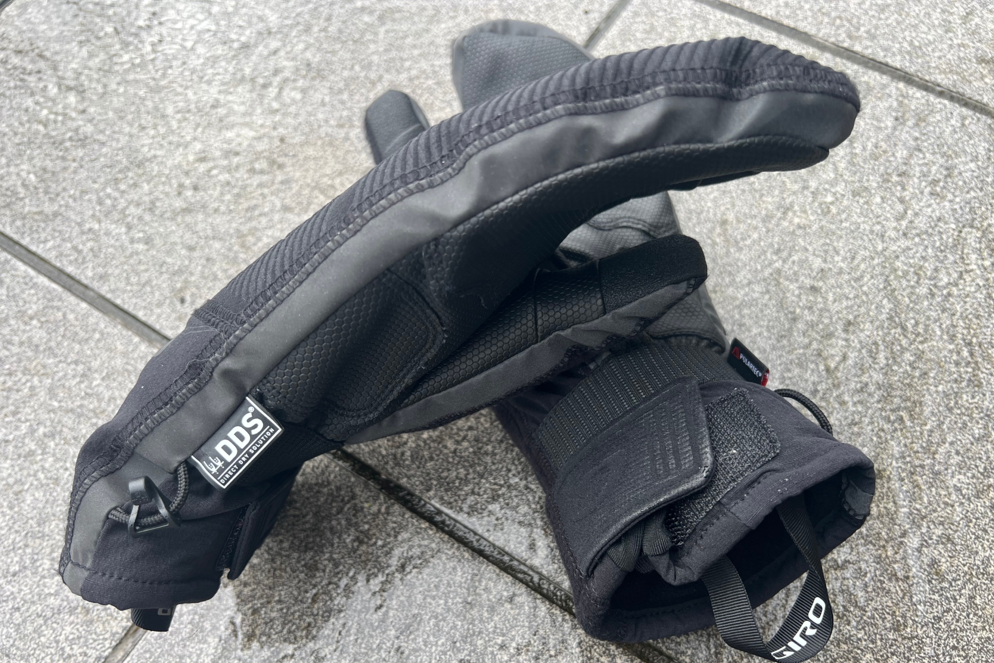 The Giro 100 Proof winter gloves side showing the fabric lable on their side on a wet tiled floor
