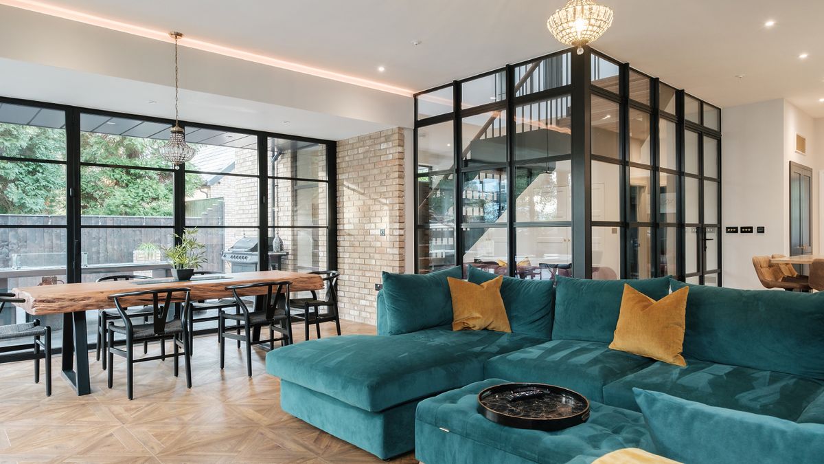 large black framed internal glass wall and windows in corner of living room with green sofa