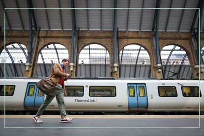 A man walking along a platform next to a Thameslink train